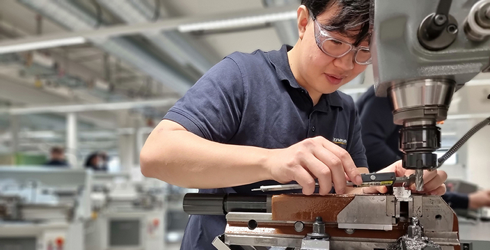 Junge Person mit Schutzbrille bei der Arbeit an einer Maschine