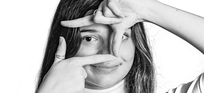 Junge, weibliche Person macht mit ihren Händen einen Ausschnitt vor ihren Augen. Junge, weibliche Person macht mit ihren Händen einen Ausschnitt vor ihren Augen.