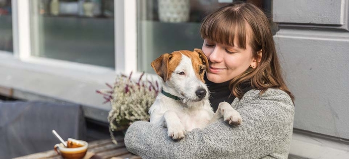 Person im Café mit einem Hund auf dem Arm