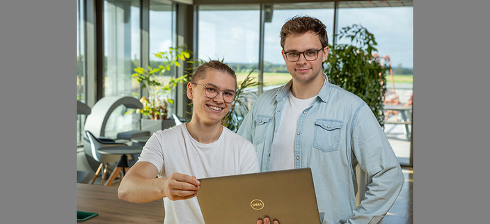 Zwei junge lächelnde Personen mit Laptop in der Hand