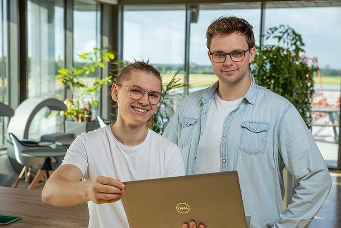 Zwei junge lächelnde Personen mit Laptop in der Hand Zwei junge lächelnde Personen mit Laptop in der Hand