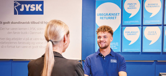 Lächelnder Mitarbeitender im Gespräch mit einer Person in der JYSK-Filiale