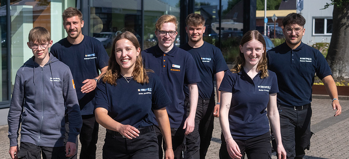 Teamfoto von einigen Auszubildenden in dunkelblauen T-Shirts und Polohemden mit Firmenlogo Teamfoto von einigen Auszubildenden in dunkelblauen T-Shirts und Polohemden mit Firmenlogo