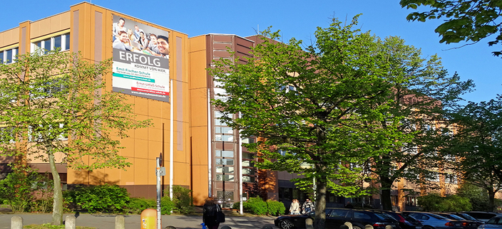 Das Gebäude der Emil-Fischer-Schule im Sonnenschein mit grünen Bäumen davor Das Gebäude der Emil-Fischer-Schule im Sonnenschein mit grünen Bäumen davor