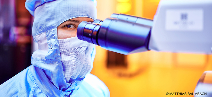 Person in Schutzkleidung sitzt an einem Mikroskop im Labor Person in Schutzkleidung sitzt an einem Mikroskop im Labor
