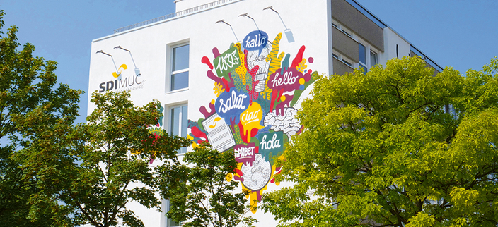 bunt angemaltes SDI Gebäude versteckt hinter Bäumen bunt angemaltes SDI Gebäude versteckt hinter Bäumen