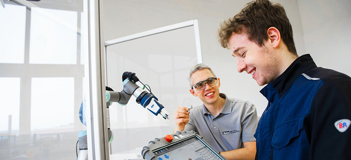 2 Personen bei der Arbeit an einer Maschine. 2 Personen bei der Arbeit an einer Maschine.