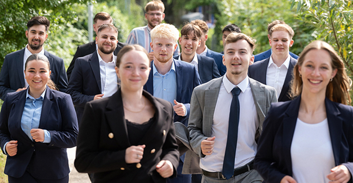 14 junge Menschen laufen auf die Kamera zu. Alle tragen Anzüge und Blazer 14 junge Menschen laufen auf die Kamera zu. Alle tragen Anzüge und Blazer