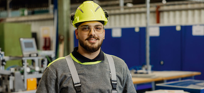Auszubildender in Arbeitskleidung mit Helm Auszubildender in Arbeitskleidung mit Helm