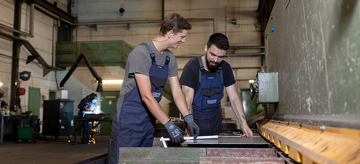 Zwei Menschen in der Werkstatt beim Bau einer Anlage Zwei Menschen in der Werkstatt beim Bau einer Anlage