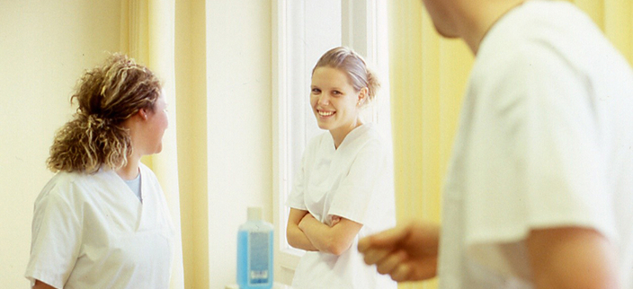 Drei Personen in weißer Pflegebekleidung im Gespräch Drei Personen in weißer Pflegebekleidung im Gespräch