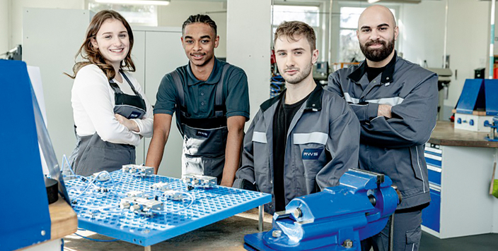 Vier junge Menschen stehen in einer Lehrwerkstatt Vier junge Menschen stehen in einer Lehrwerkstatt