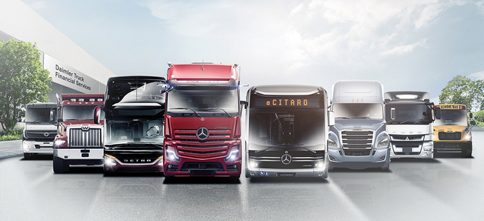 Acht verschiedene Nutzfahrzeuge sind nebeneinander aufgereiht. Es handelt sich um moderne Lkw, Busse und ein typischer gelber US-Schulbus. Im Hintergrund steht ein Gebäude mit der Aufschrift "Daimler Truck Financial Services“. Acht verschiedene Nutzfahrzeuge sind nebeneinander aufgereiht. Es handelt sich um moderne Lkw, Busse und ein typischer gelber US-Schulbus. Im Hintergrund steht ein Gebäude mit der Aufschrift "Daimler Truck Financial Services“.