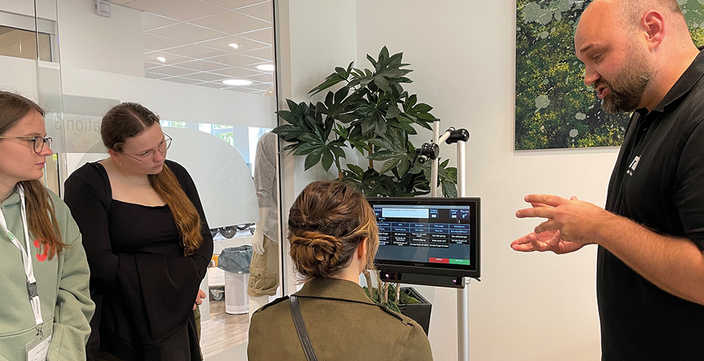Mann erklärt drei jungen Frauen Funktionen am Monitor Mann erklärt drei jungen Frauen Funktionen am Monitor