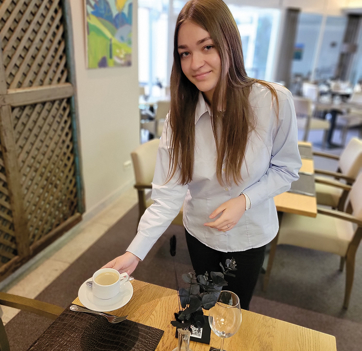 Azubi serviert eine Tasse Kaffee.