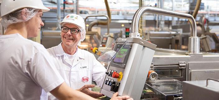 Zwei Personen stehen an Maschinen. Zwei Personen stehen an Maschinen.