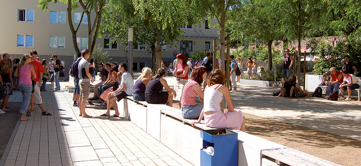 an einem sonnigen Tag sitzen und stehen Studierende im Aussenbereich der Hochschule in verschiedenen Gruppen zusammen an einem sonnigen Tag sitzen und stehen Studierende im Aussenbereich der Hochschule in verschiedenen Gruppen zusammen