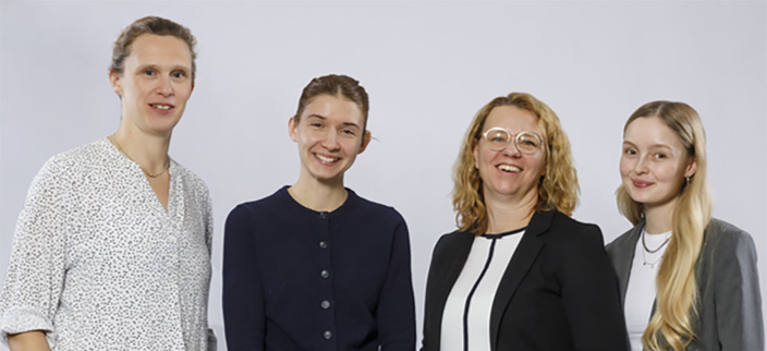 Vier Personen lächeln in die Kamera. Vier Personen lächeln in die Kamera.