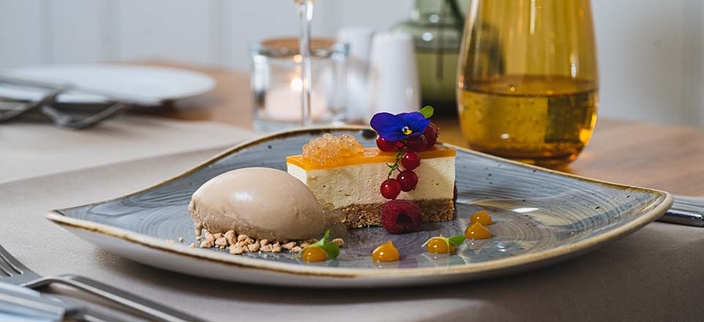 Dessertteller mit Mousse, Schnitte und Beeren, im Hintergrund eine Kerze, ein Glas und Salz- und Pfefferstreuer