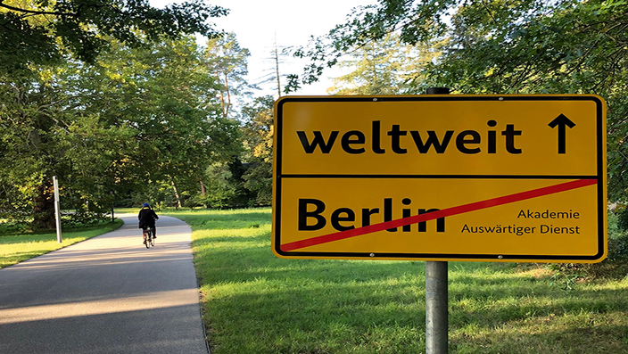 Wegweiser mit der Aufschrift Berlin durchgestrichen, weltweit mit Pfeil