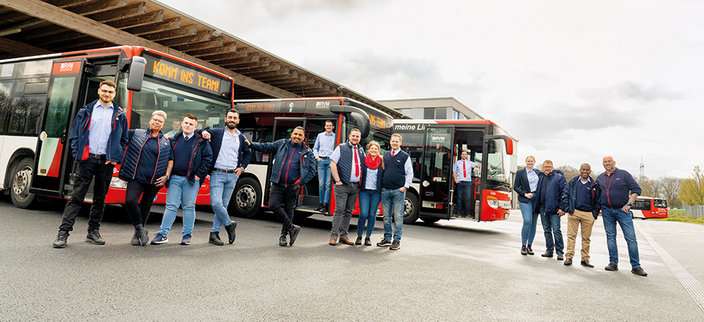 Mitarbeitende stehen in Gruppen vor Bussen