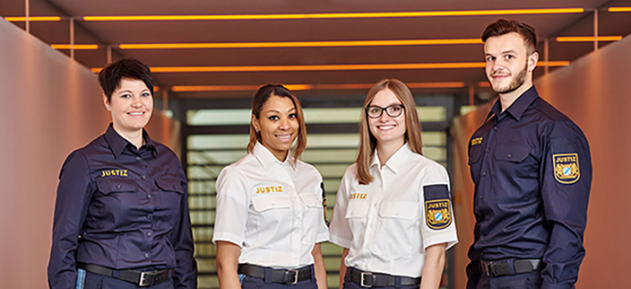 Vier Personen in Uniform lächeln in die Kamera.