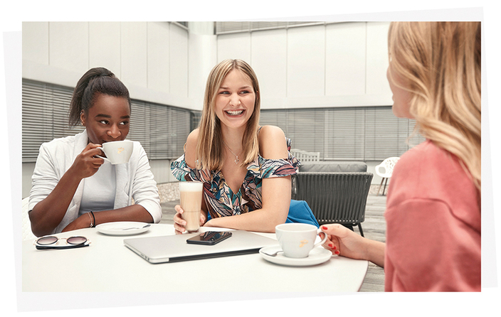 Drei junge Menschen sitzen miteinander am Tisch und trinken Kaffee Drei junge Menschen sitzen miteinander am Tisch und trinken Kaffee
