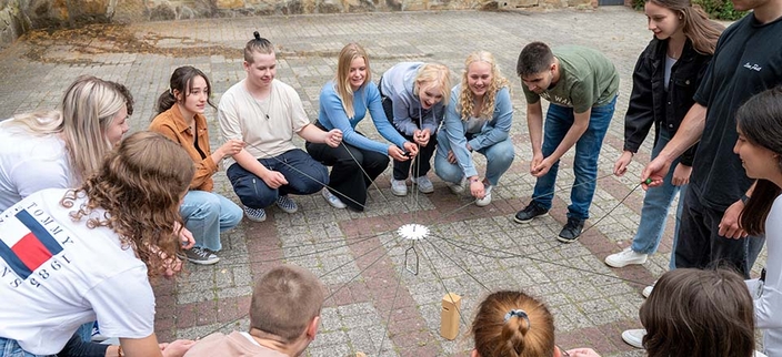 Junge Menschen spielen gemeinsam ein Geschicklichkeitsspiel Junge Menschen spielen gemeinsam ein Geschicklichkeitsspiel