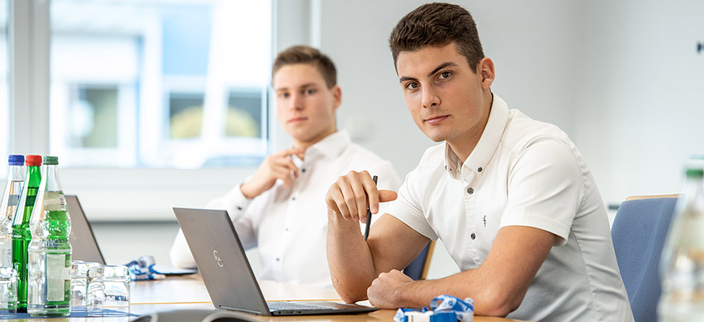Zwei junge Männer vor ihren Laptops am Konferenztisch Zwei junge Männer vor ihren Laptops am Konferenztisch