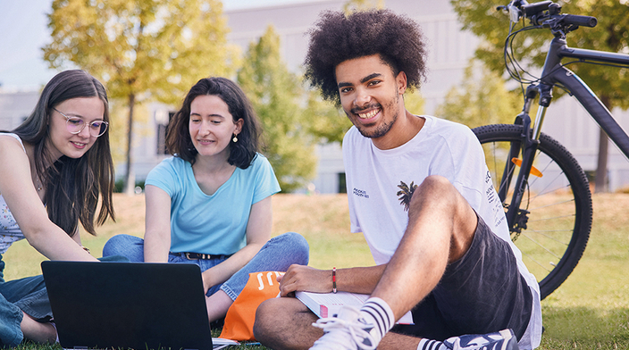 Kleine Gruppe junger Menschen sitzt im freien vor Laptop Kleine Gruppe junger Menschen sitzt im freien vor Laptop