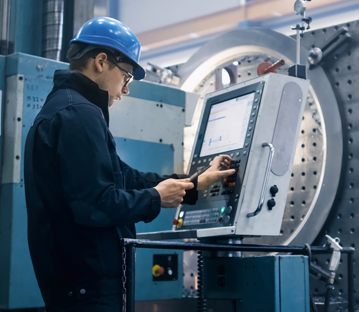Person mit Schutzhelm bedient eine Maschine Person mit Schutzhelm bedient eine Maschine