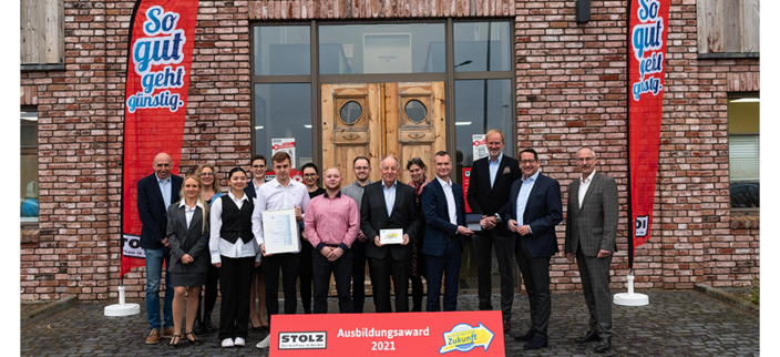 15 Menschen stehen vor Firmeneingang (Gruppenfoto)