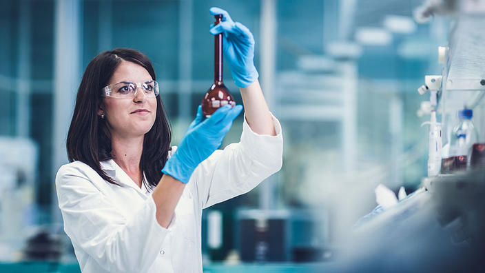 Pharmakantin hält ein roten Glaskolben in der Hand Pharmakantin hält ein roten Glaskolben in der Hand