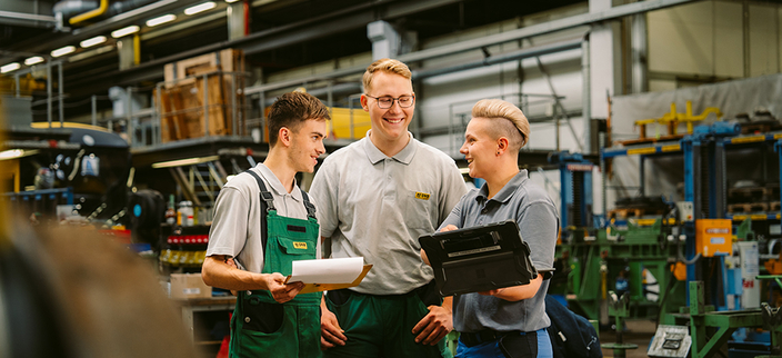 Drei Mitarbeitende in Arbeitskleidung bei einer Besprechung in der Werkstatt