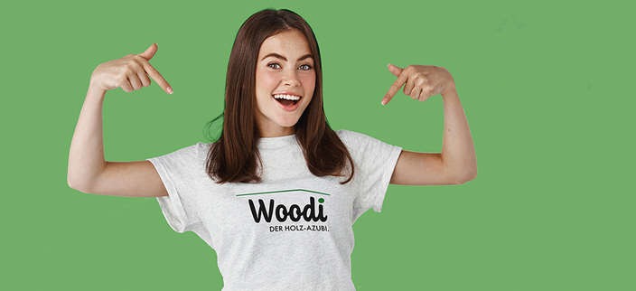 Weibliche Person mit einem "Woodi" T-Shirt vor grünem Hintergrund.