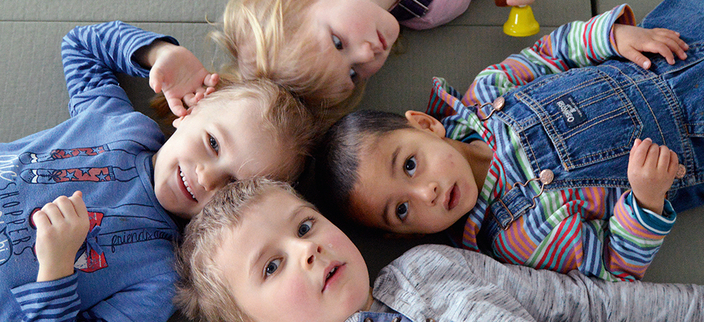 Vier Kinder liegen Kopf an Kopf im Kreis