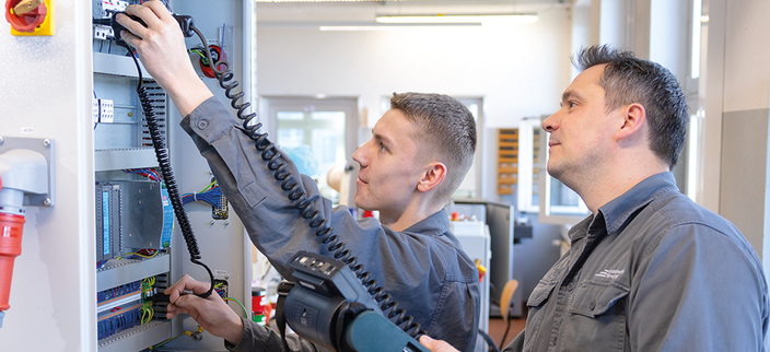 Zwei Mitarbeitende prüfen einen Sicherungskasten Zwei Mitarbeitende prüfen einen Sicherungskasten