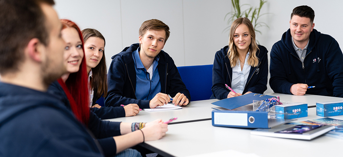 Sechs junge Menschen am Tisch im Gespräch Sechs junge Menschen am Tisch im Gespräch