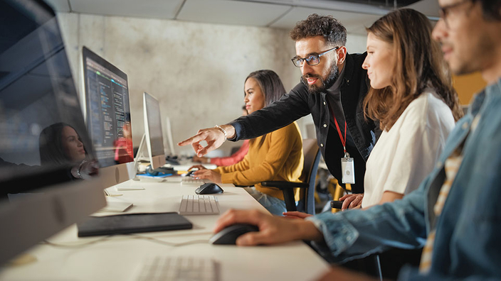 Personen sitzen vor Computerbildschirmen Personen sitzen vor Computerbildschirmen
