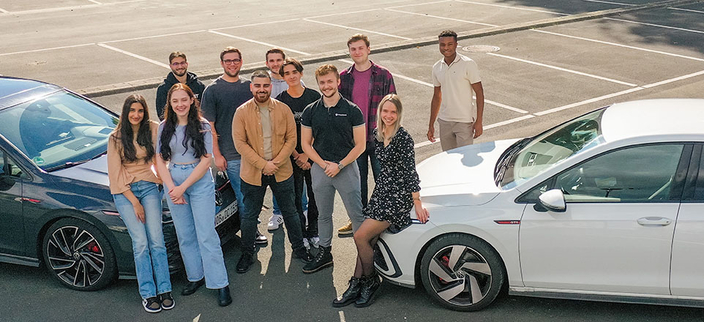 Gruppenfoto von elf Auszubildenden mit zwei Volkswagen