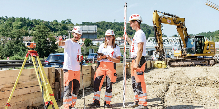 Drei Bauarbeiter/innen vermessen auf Baustelle Drei Bauarbeiter/innen vermessen auf Baustelle