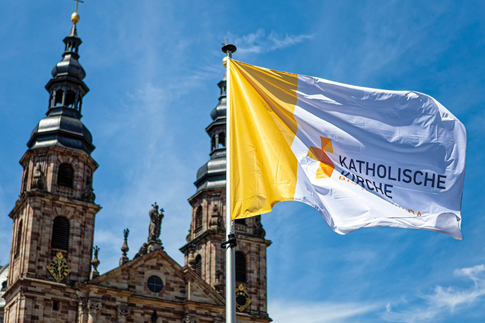 Wehende Fahne des Bistums Fulda vor Kirche Wehende Fahne des Bistums Fulda vor Kirche