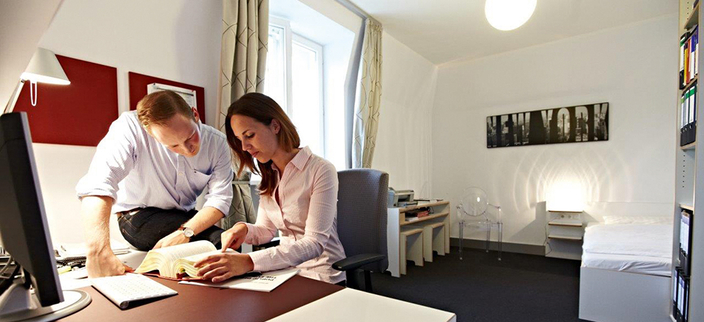 Zwei junge Menschen am Schreibtisch lesen in einem Buch Zwei junge Menschen am Schreibtisch lesen in einem Buch