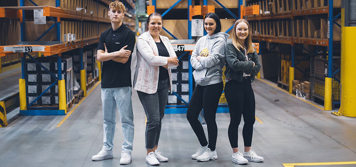 Vier junge Personen mit verschränkten Armen in der Lagerhalle des Unternehmens Vier junge Personen mit verschränkten Armen in der Lagerhalle des Unternehmens