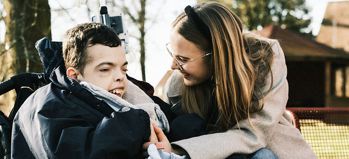 junge, männliche Person mit Behinderung und junge, weibliche Person fröhlich miteinander im Freien junge, männliche Person mit Behinderung und junge, weibliche Person fröhlich miteinander im Freien