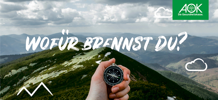 Eine Hand hält einen Kompass vor einer Kulisse aus Bergen und Wolken, Bildaufschrift: Wofür brennst du? Eine Hand hält einen Kompass vor einer Kulisse aus Bergen und Wolken, Bildaufschrift: Wofür brennst du?
