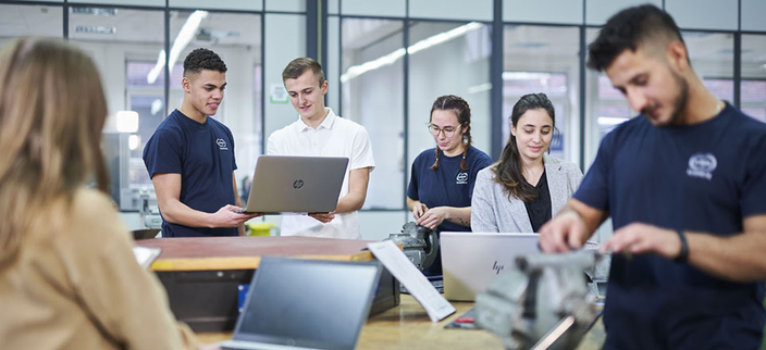Vier Personen arbeiten an Computern und zwei Personen arbeiten an elektromechanischen Komponenten Vier Personen arbeiten an Computern und zwei Personen arbeiten an elektromechanischen Komponenten