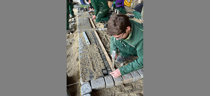 Landschaftsgärtner in grüner Arbeitskleidung beim Verlegen von Steinen Landschaftsgärtner in grüner Arbeitskleidung beim Verlegen von Steinen