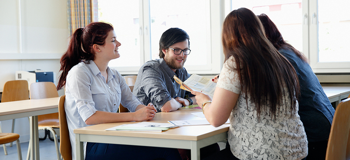 Schüler/innen unterhalten sich am Tisch Schüler/innen unterhalten sich am Tisch