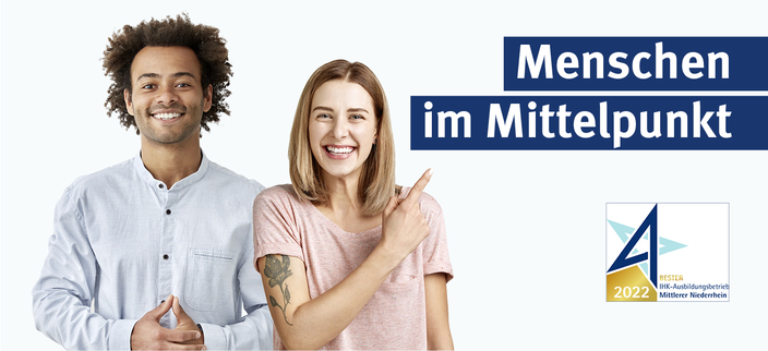 Zwei Personen, eine zeigt auf den Slogan Menschen im Mittelpunkt